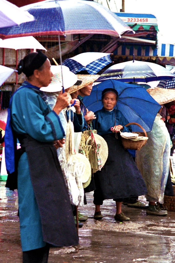 Anshun Sunday Market: 安顺星期七农民市场 ladies waiting to go home in the rain